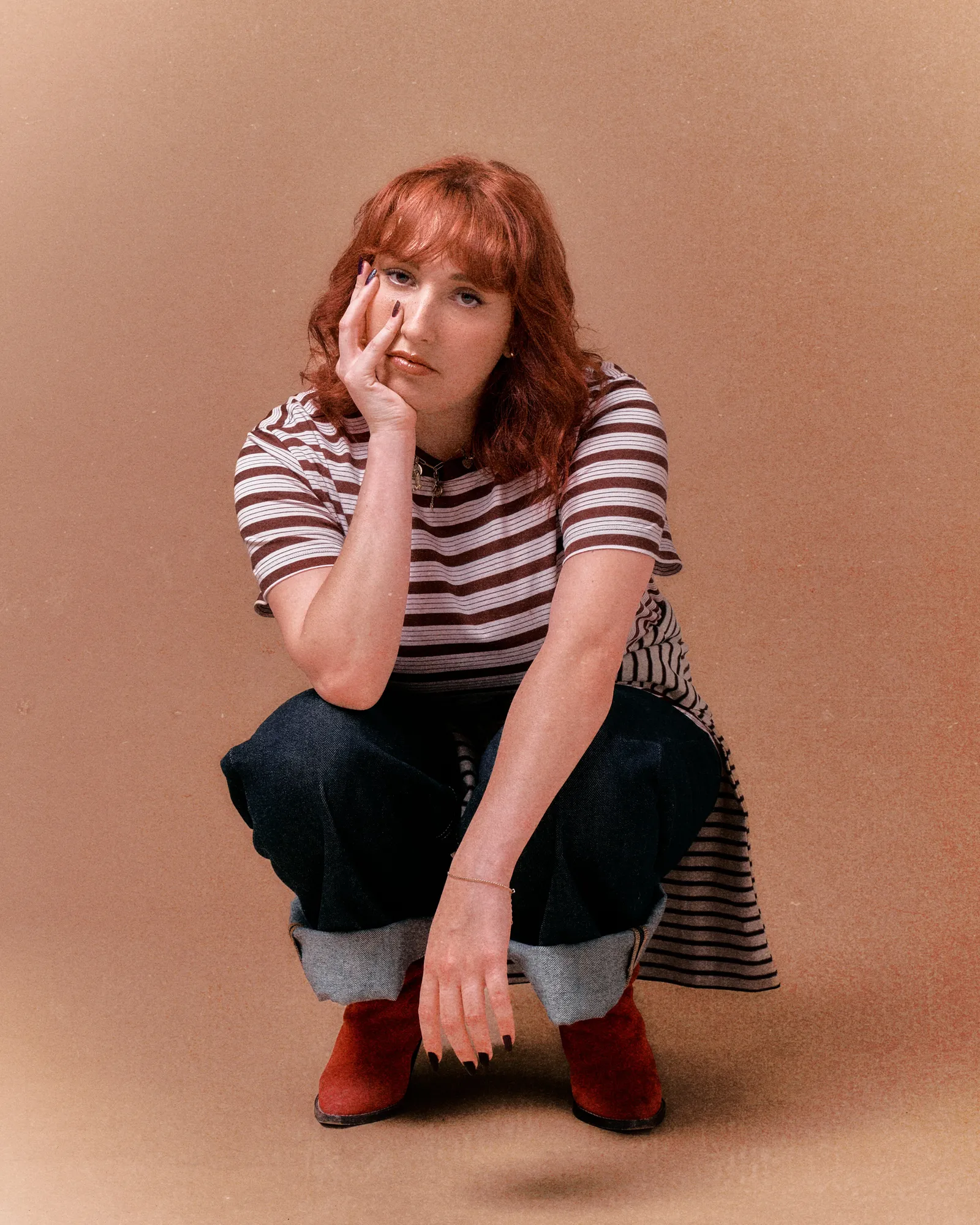 Photo de Lisa Pariente, face à nous accroupie. Elle tiens son visage dans sa main droite
