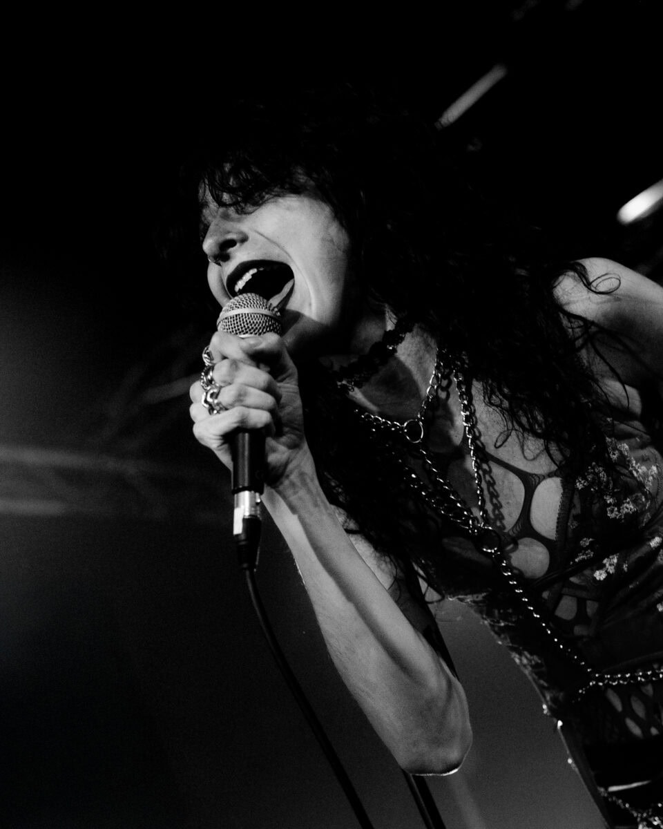un gros plan sur le micro et le visage de la chanteuse du groupe. Elle chante